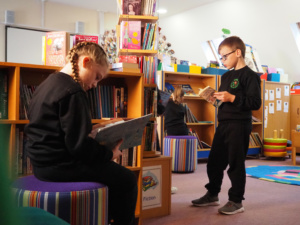 Two young kids reading books in the school library