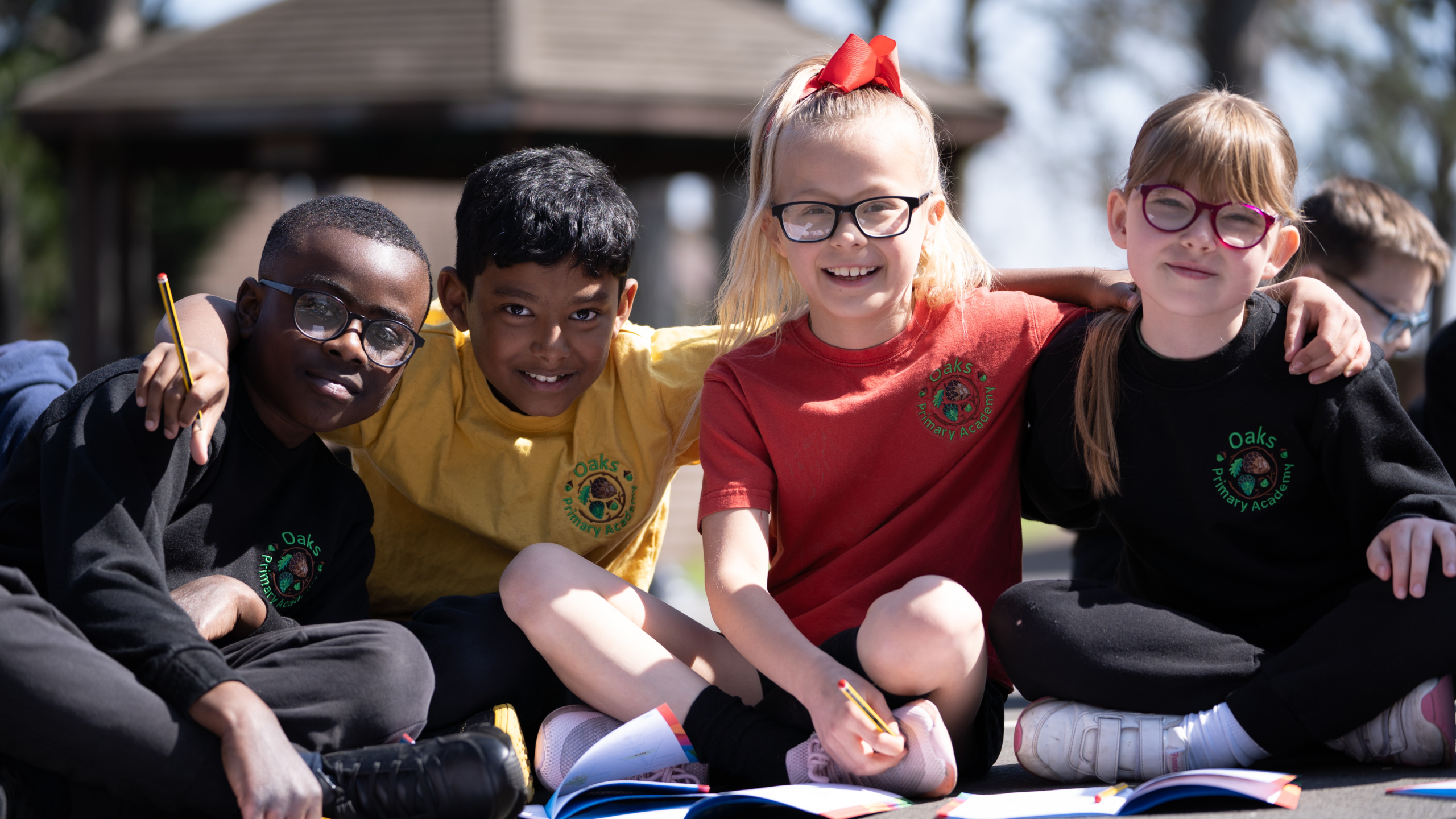 Four young students of different race sitting next to each other while smiling at the camera